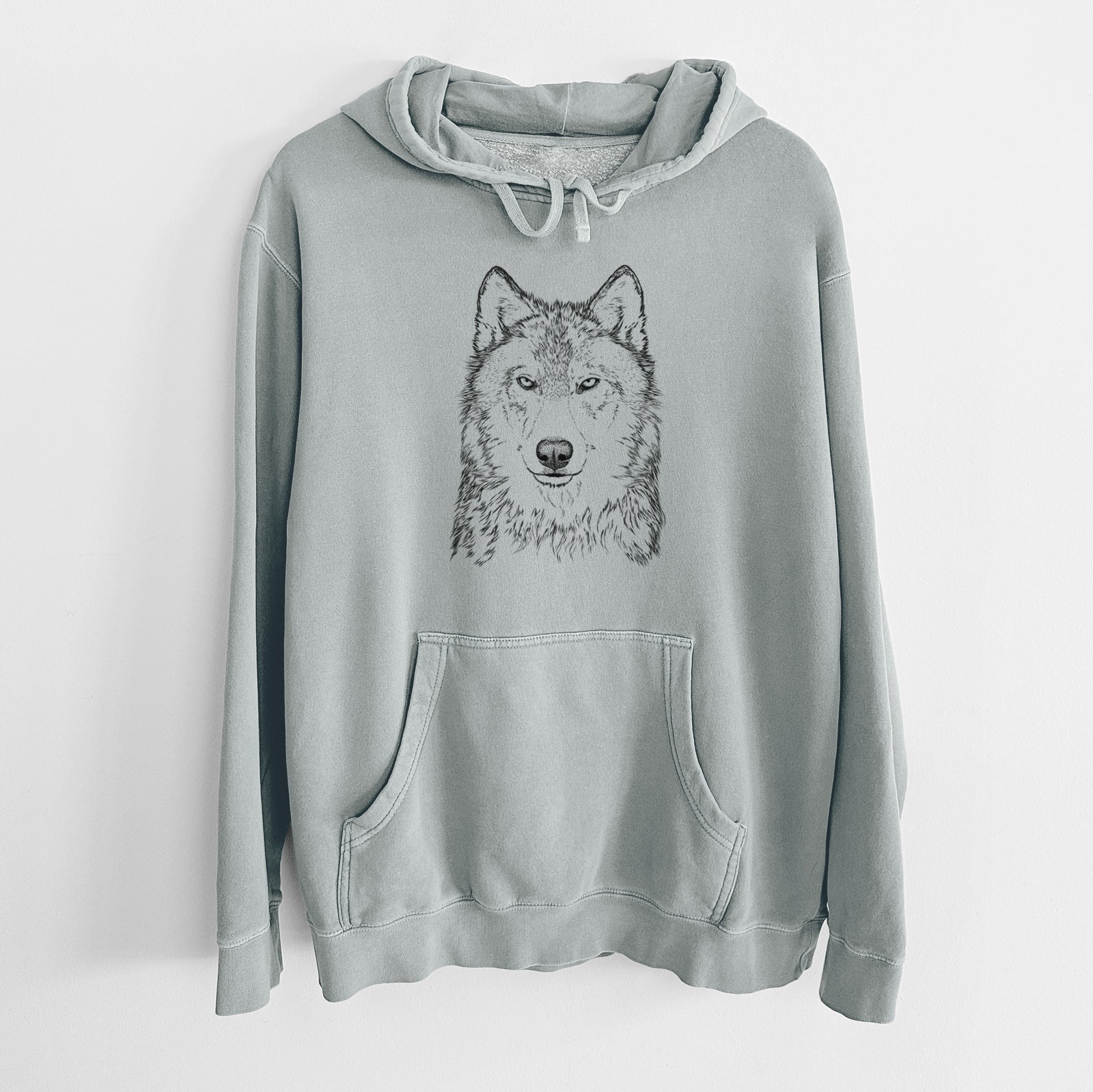 Sage green pigment dyed hoodie laid flat, printed with a detailed black ink portrait of a grey wolf facing forward.