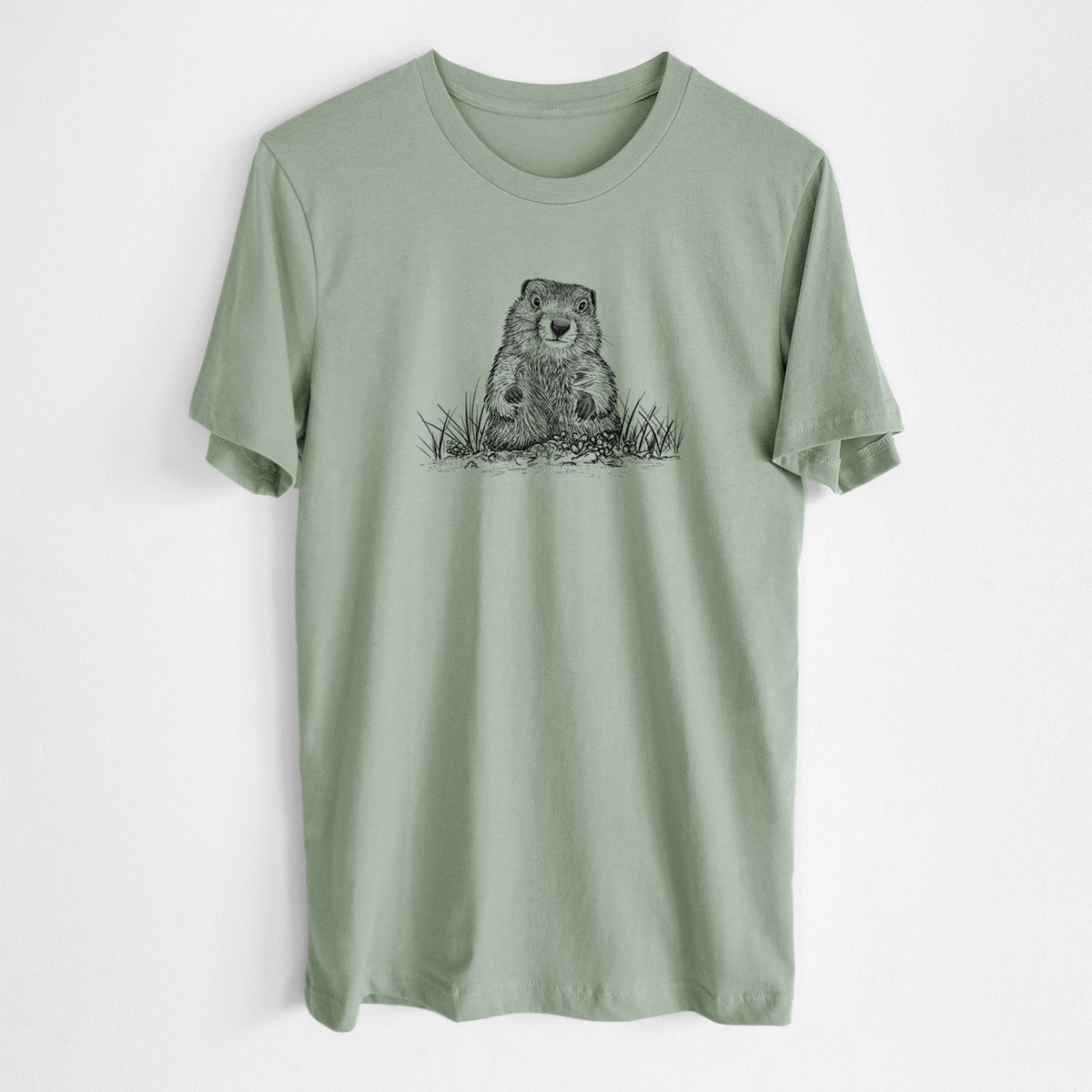 Sage green lightweight cotton t-shirt laid flat, printed with a black ink illustration of a groundhog peeking out of its burrow among grass.