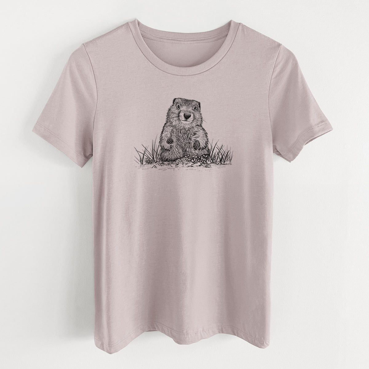 Pink gravel women's relaxed fit cotton t-shirt laid flat, printed with a black ink illustration of a groundhog peeking out of its burrow among grass.