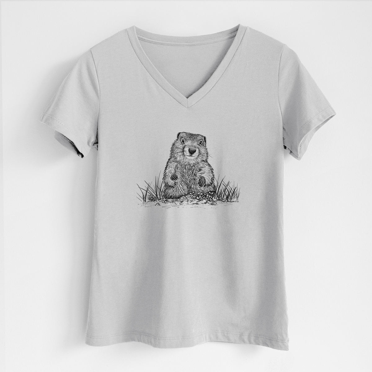 Lunar grey women's relaxed fit cotton V-neck t-shirt laid flat, printed with a black ink illustration of a groundhog peeking out of its burrow among grass.