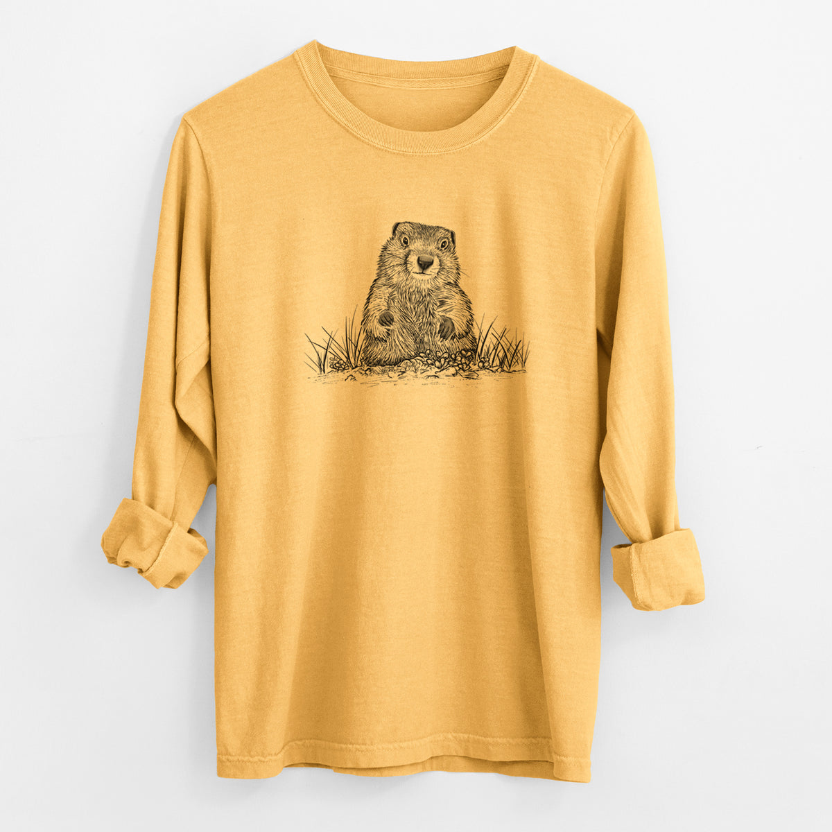 Golden wheat yellow Comfort Colors long sleeve shirt laid flat with the cuffs rolled, printed with a black ink illustration of a groundhog peeking out of its burrow among grass.