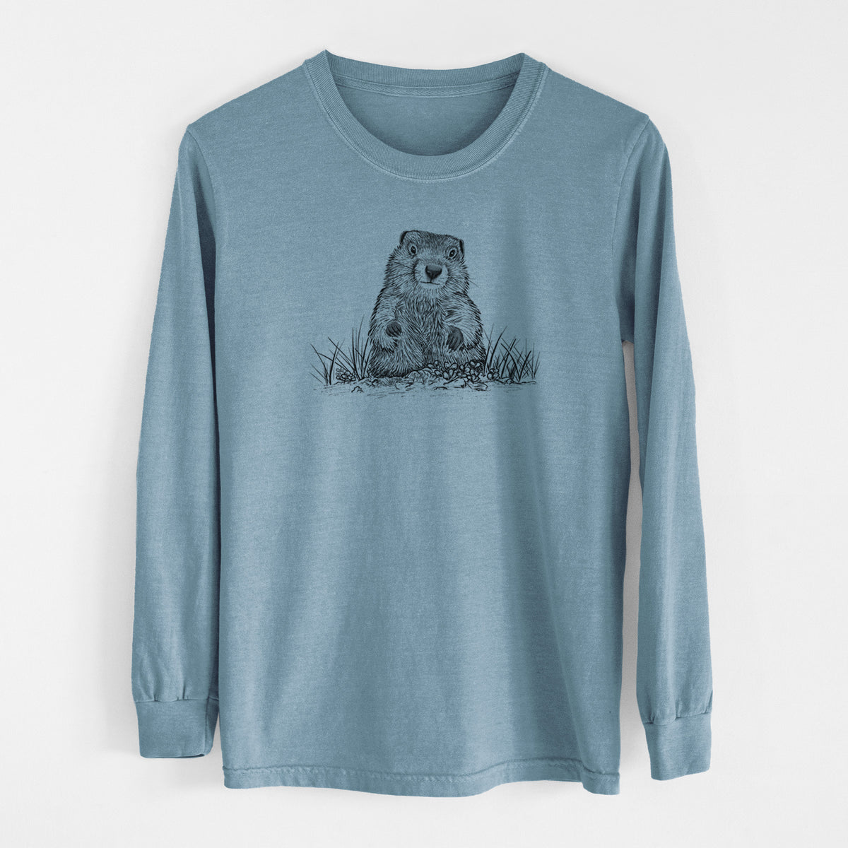 Steel blue Comfort Colors long sleeve shirt laid flat, printed with a black ink illustration of a groundhog peeking out of its burrow among grass.