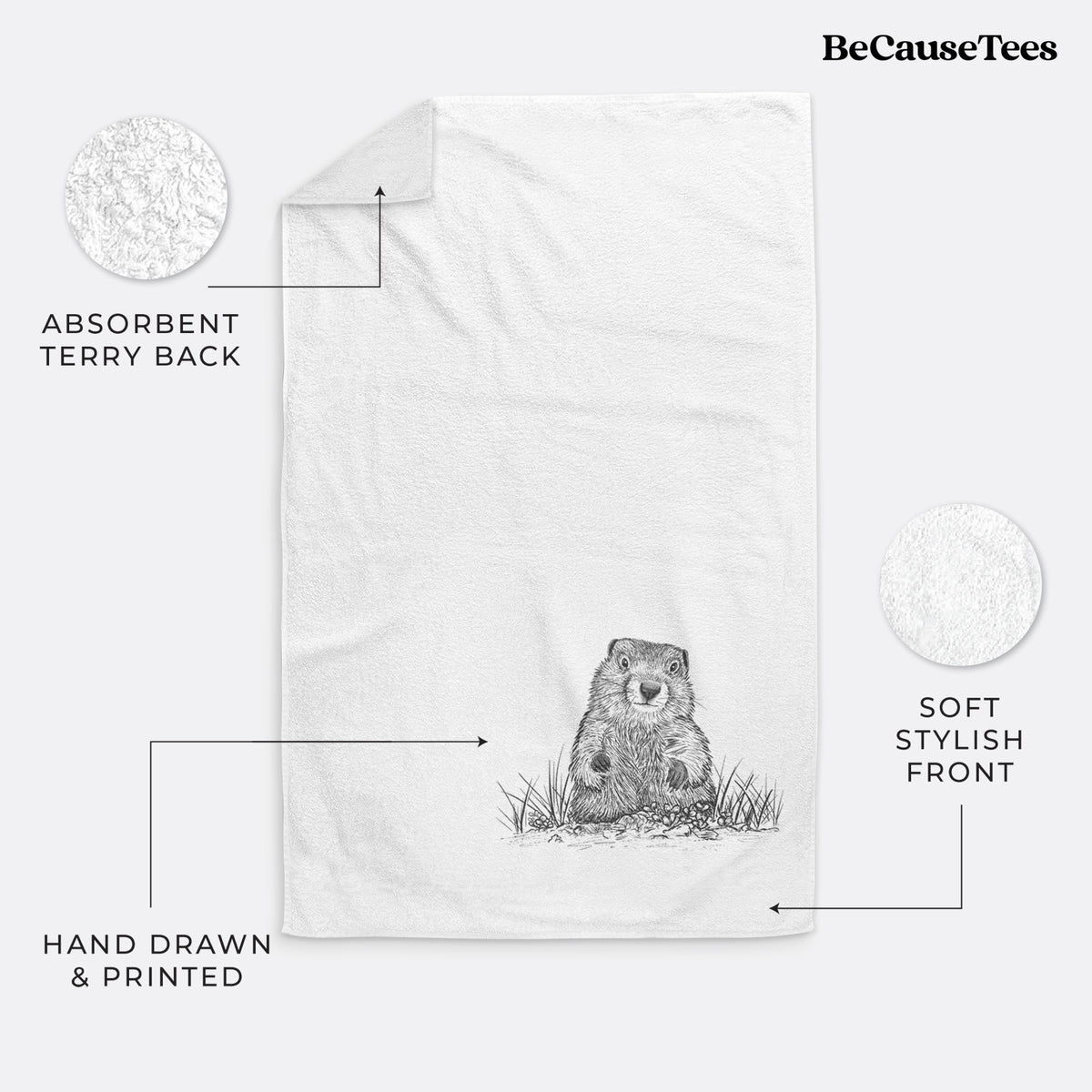 White hand towel printed with a black ink illustration of a groundhog peeking out of its burrow among grass.