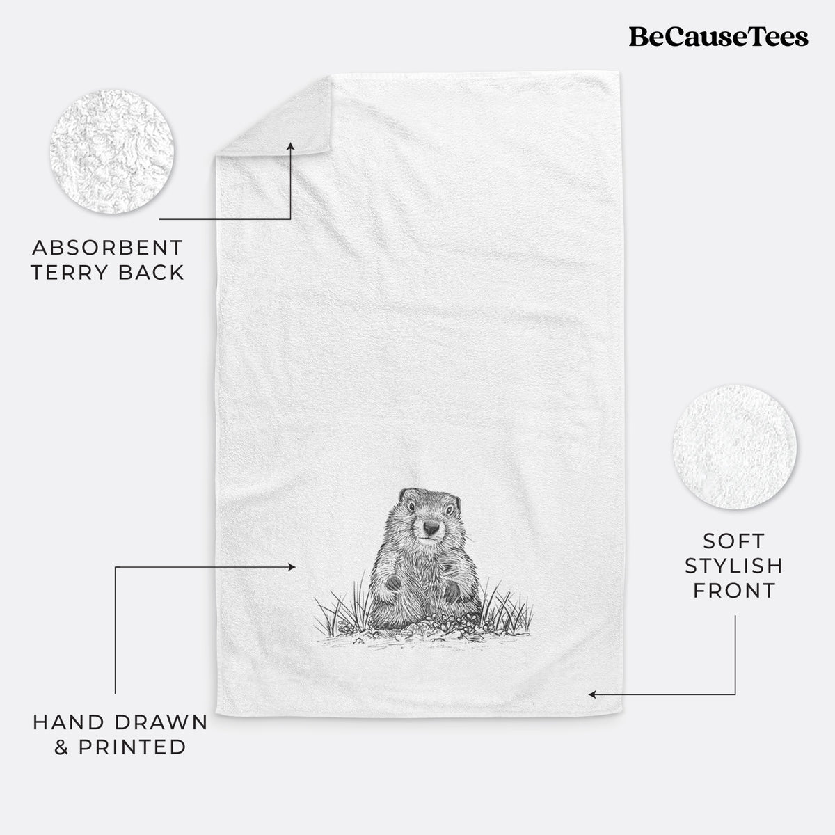 White hand towel printed with a black ink illustration of a groundhog peeking out of its burrow among grass.