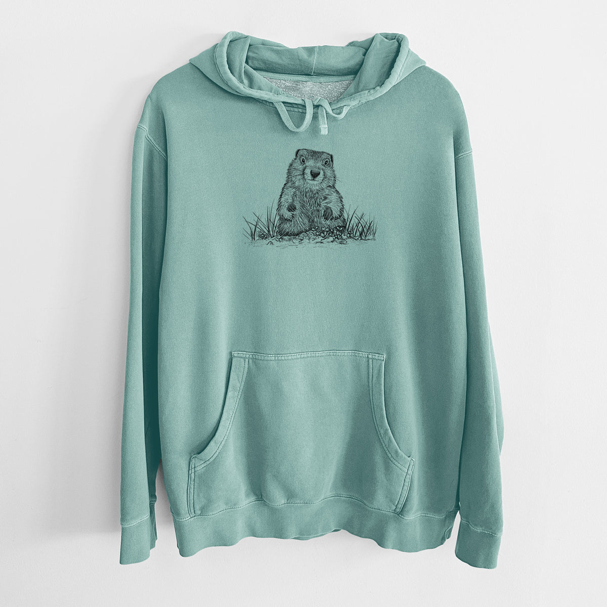 Mint green pigment dyed hoodie laid flat, printed with a black ink illustration of a groundhog peeking out of its burrow among grass.