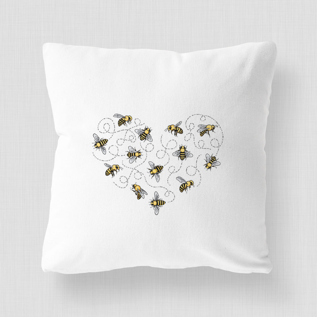 White pillow cover printed with a heart shape made of small bees and looping flight trails.