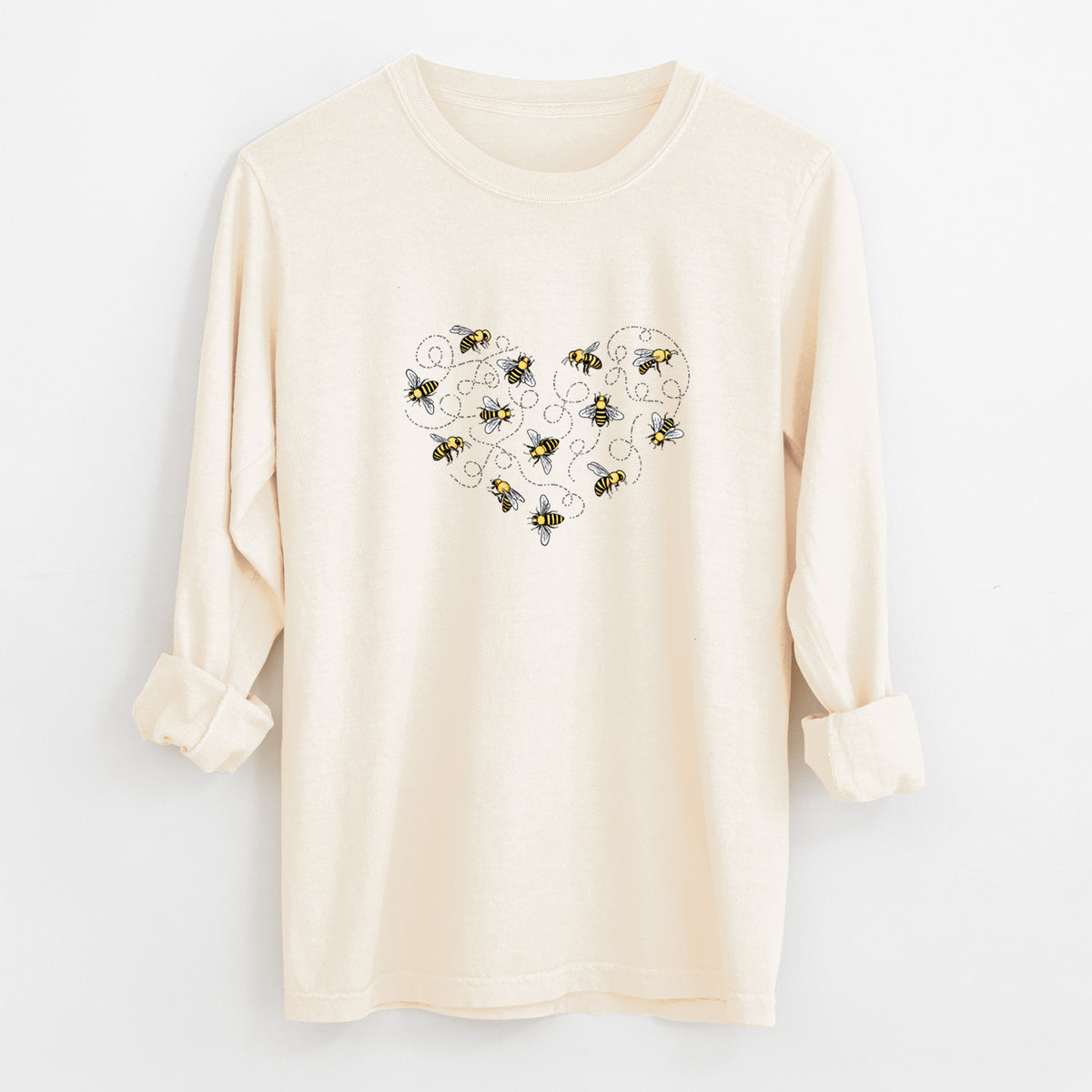 Ivory Comfort Colors long sleeve shirt laid flat with the cuffs rolled, printed with a heart shape made of small bees and looping flight trails.