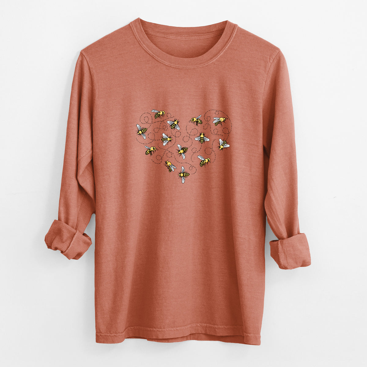Yam burnt orange Comfort Colors long sleeve shirt laid flat with the cuffs rolled, printed with a heart shape made of small bees and looping flight trails.