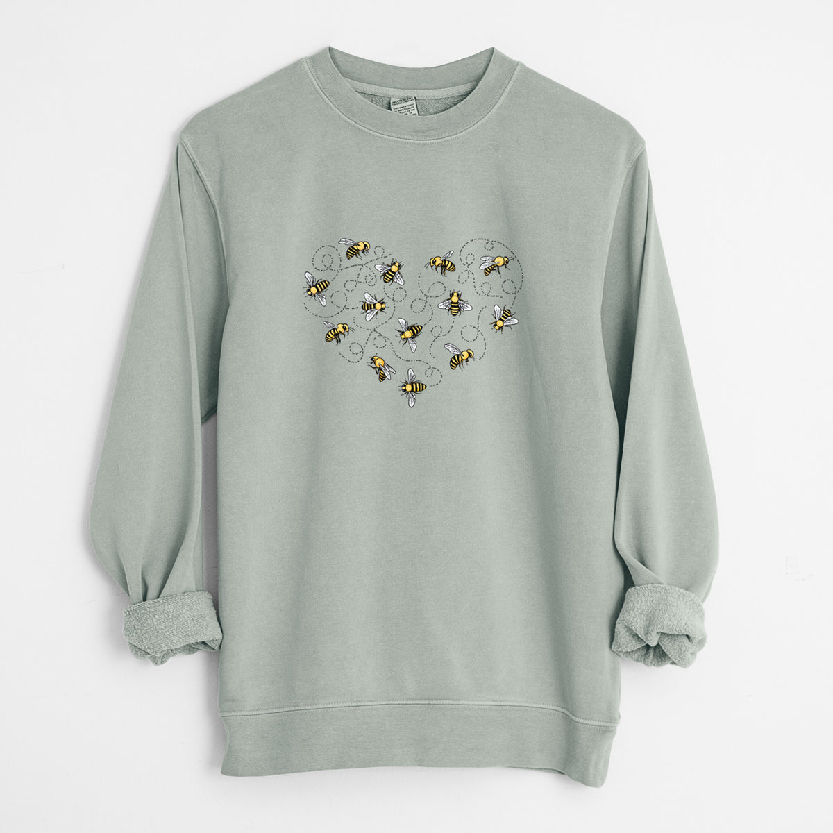Sage green pigment dyed crewneck sweatshirt laid flat with the sleeves rolled, printed with a heart shape made of small bees and looping flight trails.