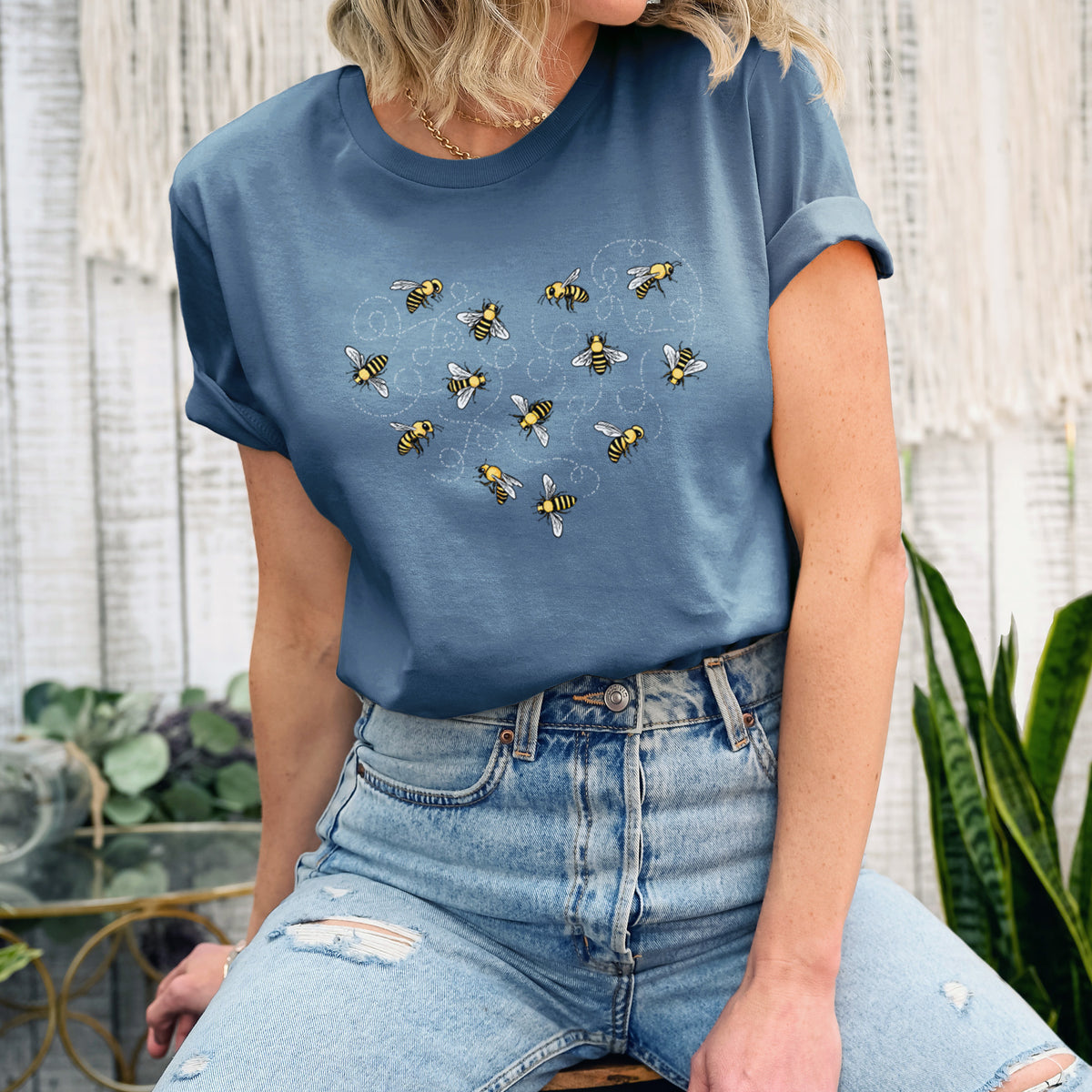 Woman wearing a steel blue lightweight cotton t-shirt printed with a heart shape made of small bees and looping flight trails.