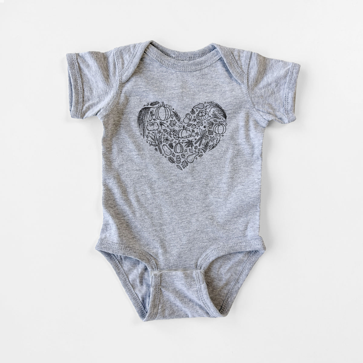 Grey baby bodysuit laid flat, printed with a heart shape filled with black ink autumn leaves, acorns, pumpkins and mushrooms.