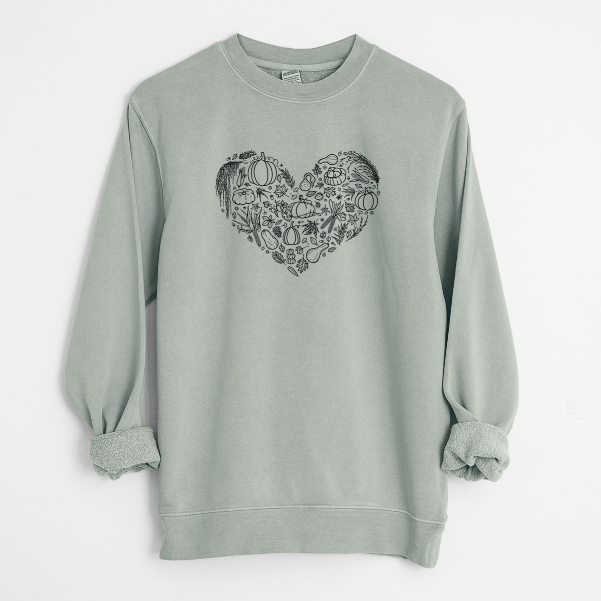 Sage green pigment dyed crewneck sweatshirt laid flat with the sleeves rolled, printed with a heart shape filled with black ink autumn leaves, acorns, pumpkins and mushrooms.