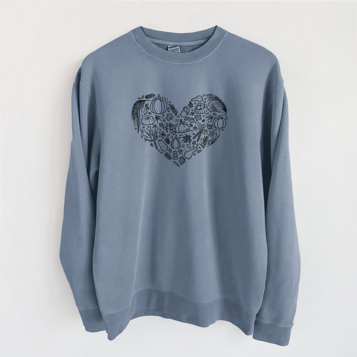 Slate blue pigment dyed crewneck sweatshirt laid flat, printed with a heart shape filled with black ink autumn leaves, acorns, pumpkins and mushrooms.
