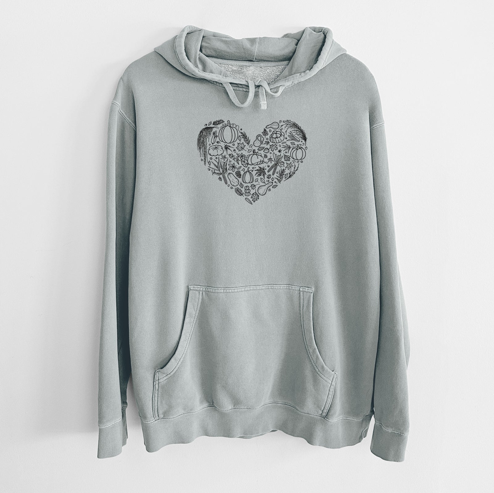 Sage green pigment dyed hoodie laid flat, printed with a heart shape filled with black ink autumn leaves, acorns, pumpkins and mushrooms.