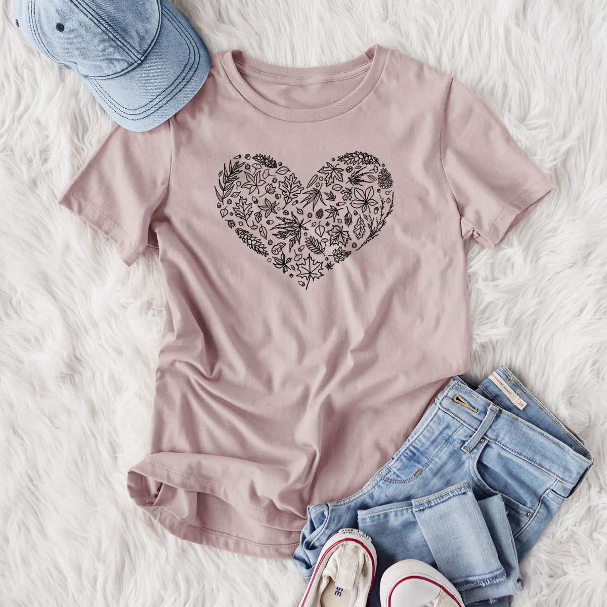 Women's relaxed fit cotton t-shirt printed with a heart shape filled with black ink autumn leaves, styled flat on a white faux fur rug with jeans.
