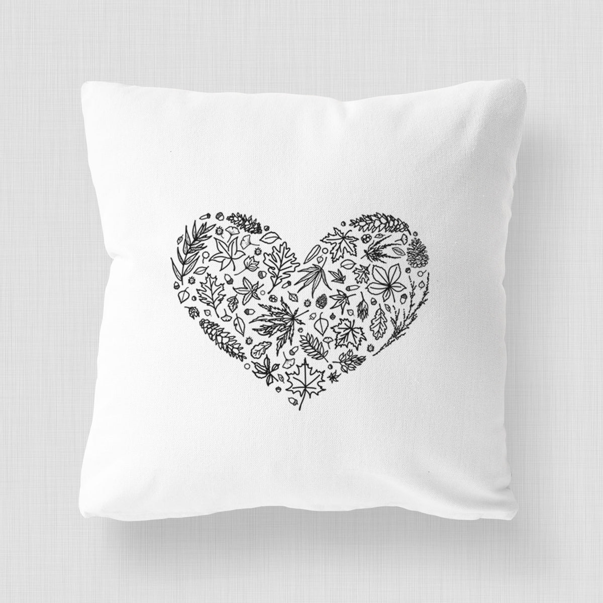 White pillow cover printed with a heart shape filled with black ink autumn leaves.