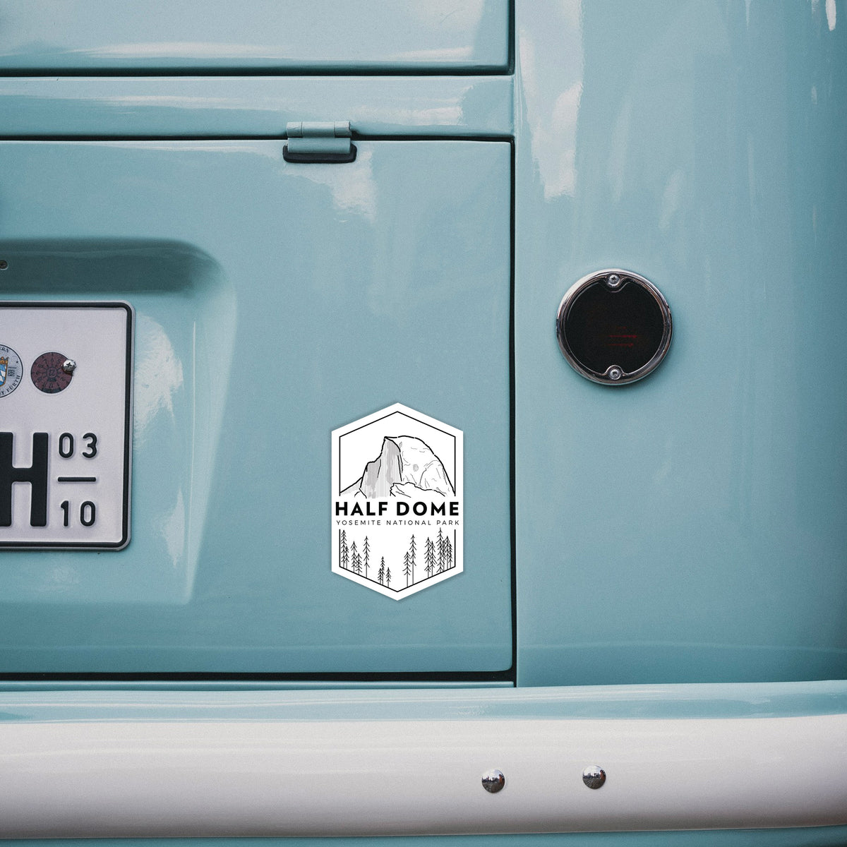 4 inch vinyl decal of a black line art badge of Half Dome above a pine forest, with the words Half Dome, Yosemite National Park on the back of a van.