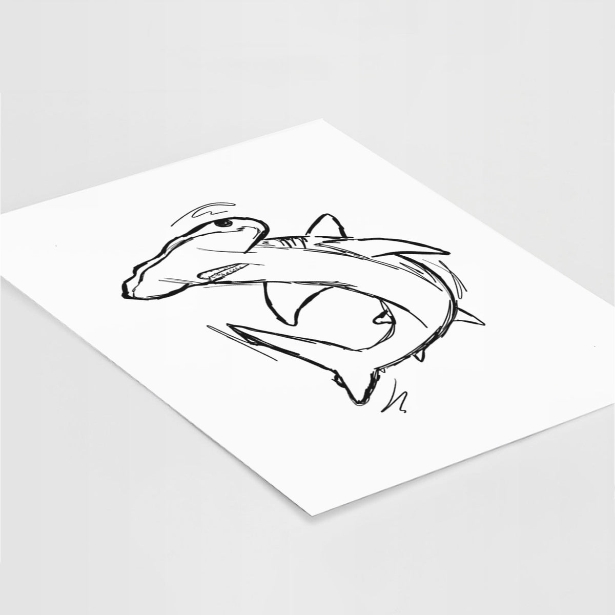 Art print of a black ink illustration of a hammerhead shark swimming in a curve, lying at an angle on a white surface.