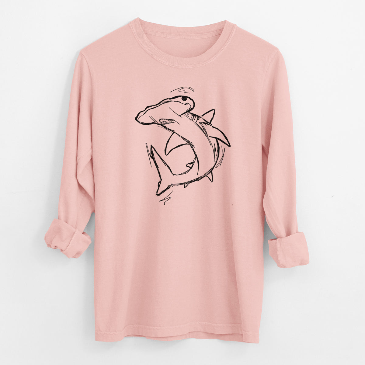 Peachy Comfort Colors long sleeve shirt laid flat with the cuffs rolled, printed with a black ink illustration of a hammerhead shark swimming in a curve.