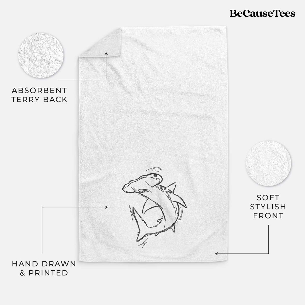 White hand towel printed with a black ink illustration of a hammerhead shark swimming in a curve.