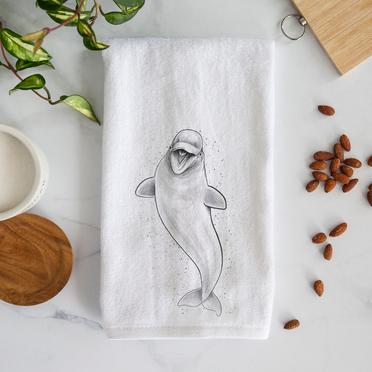 White hand towel printed with a black ink illustration of a smiling beluga whale swimming upward.