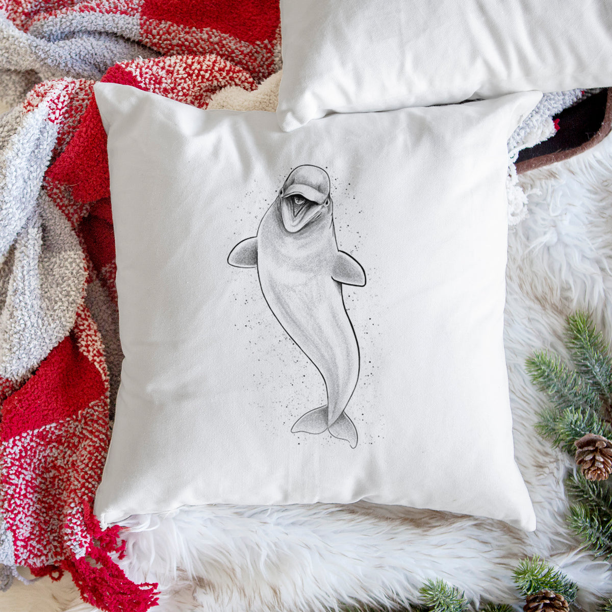 White pillow cover printed with a black ink illustration of a smiling beluga whale swimming upward, on a woven chair.