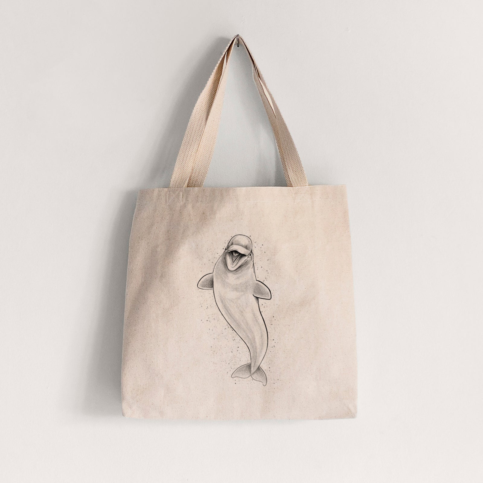 Natural canvas tote bag printed with a black ink illustration of a smiling beluga whale swimming upward.