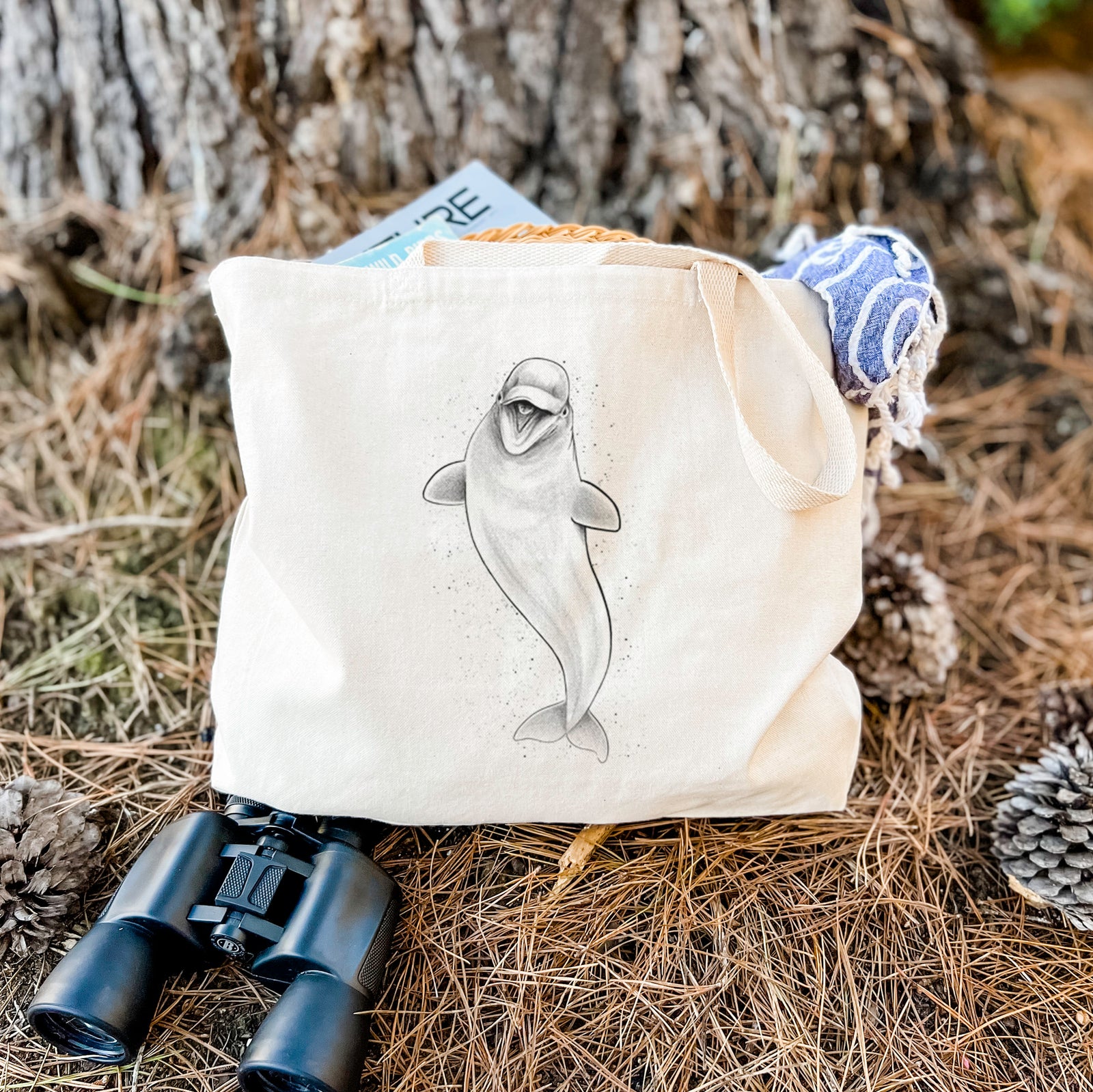 Natural canvas tote bag printed with a black ink illustration of a smiling beluga whale swimming upward.