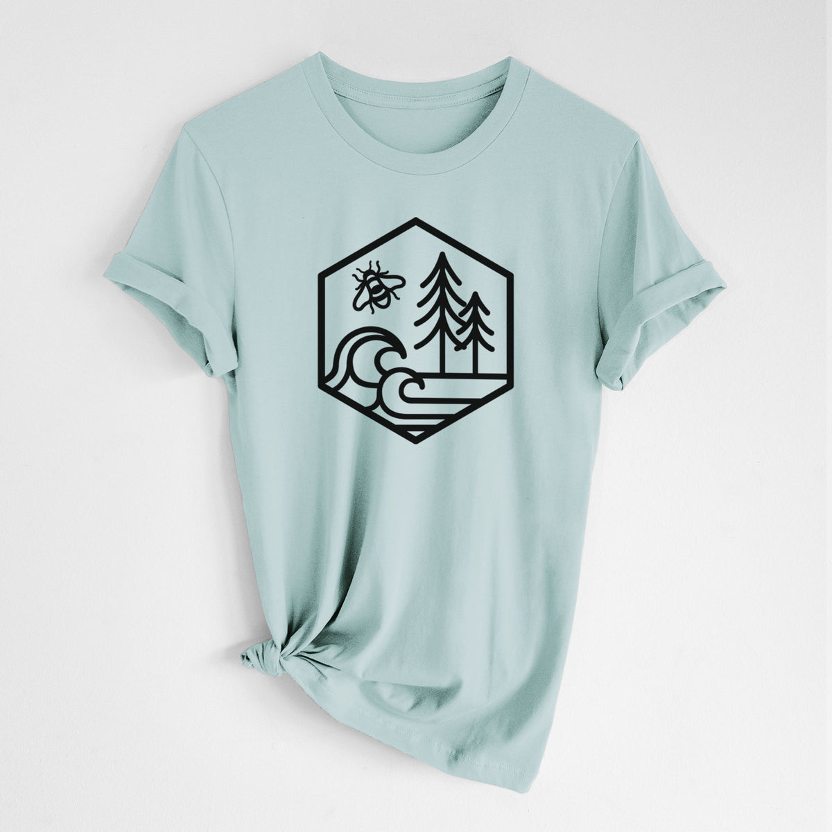 Dusty blue lightweight cotton t-shirt laid flat with the sleeves rolled, printed with a black line art hexagon holding a bee, ocean waves and pine trees.