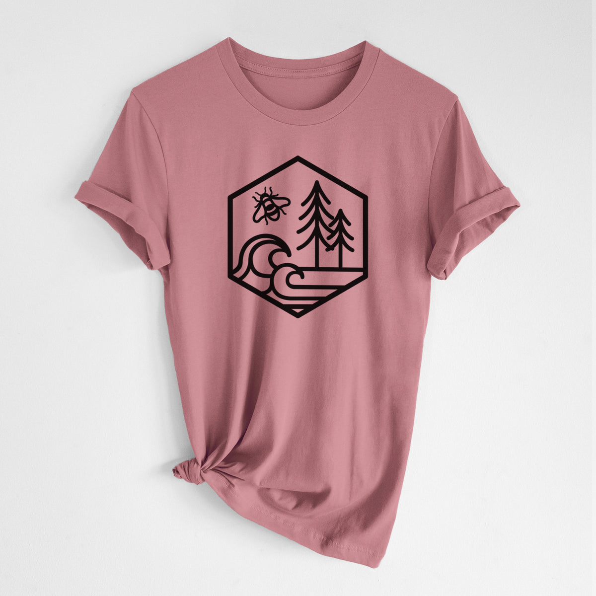 Mauve pink lightweight cotton t-shirt laid flat with the sleeves rolled, printed with a black line art hexagon holding a bee, ocean waves and pine trees.