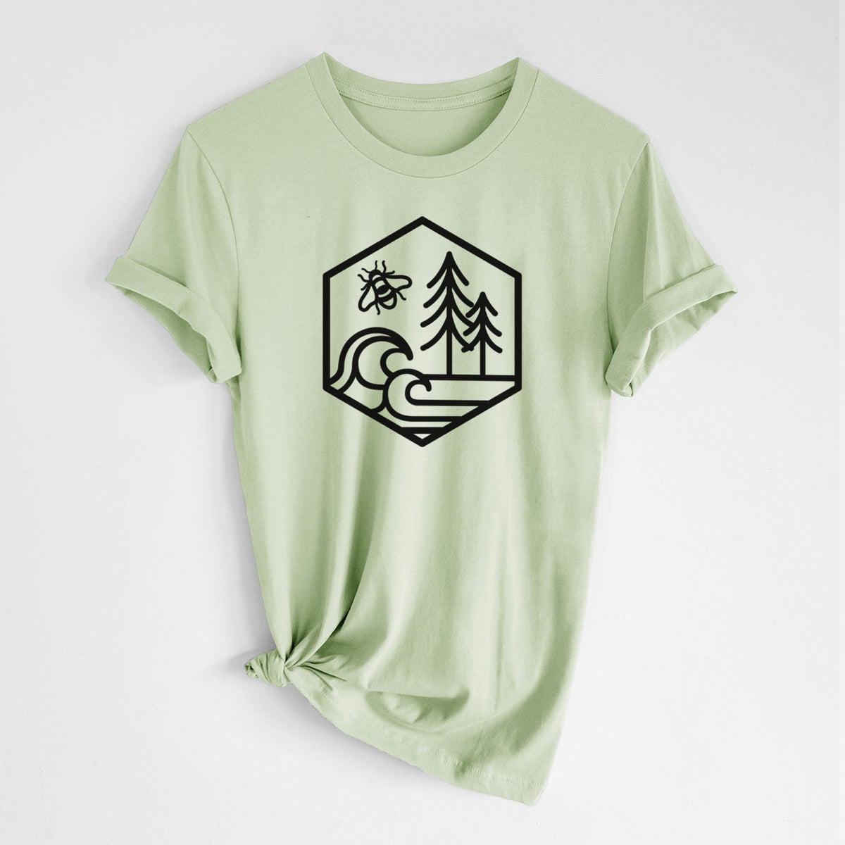 Spring green lightweight cotton t-shirt laid flat with the sleeves rolled, printed with a black line art hexagon holding a bee, ocean waves and pine trees.