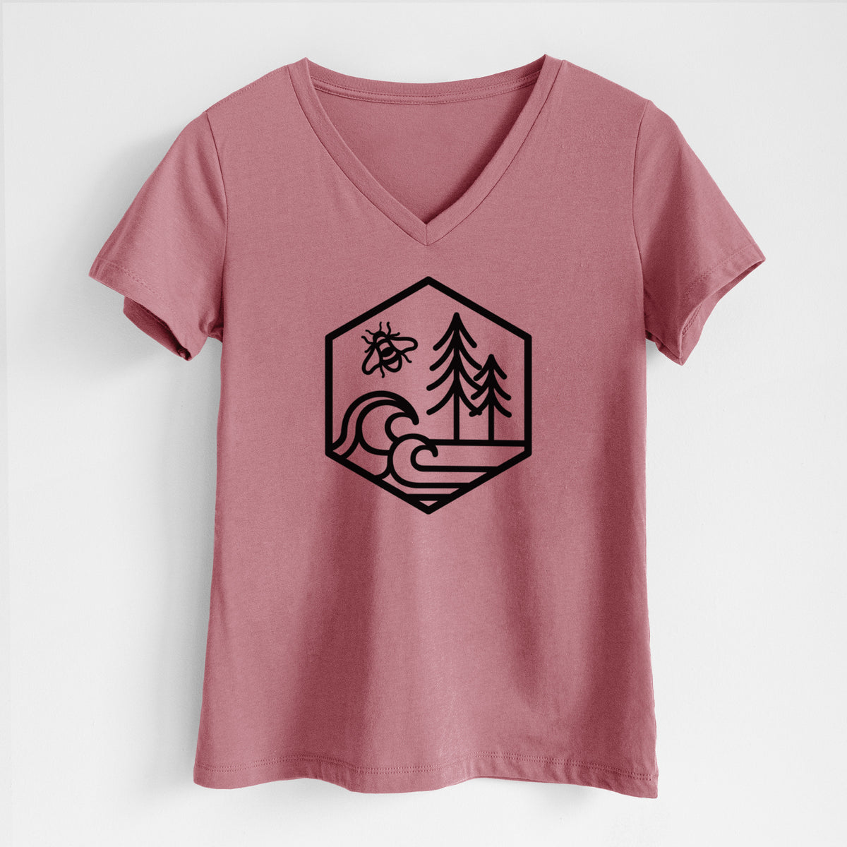 Mauve pink women's relaxed fit cotton V-neck t-shirt laid flat, printed with a black line art hexagon holding a bee, ocean waves and pine trees.