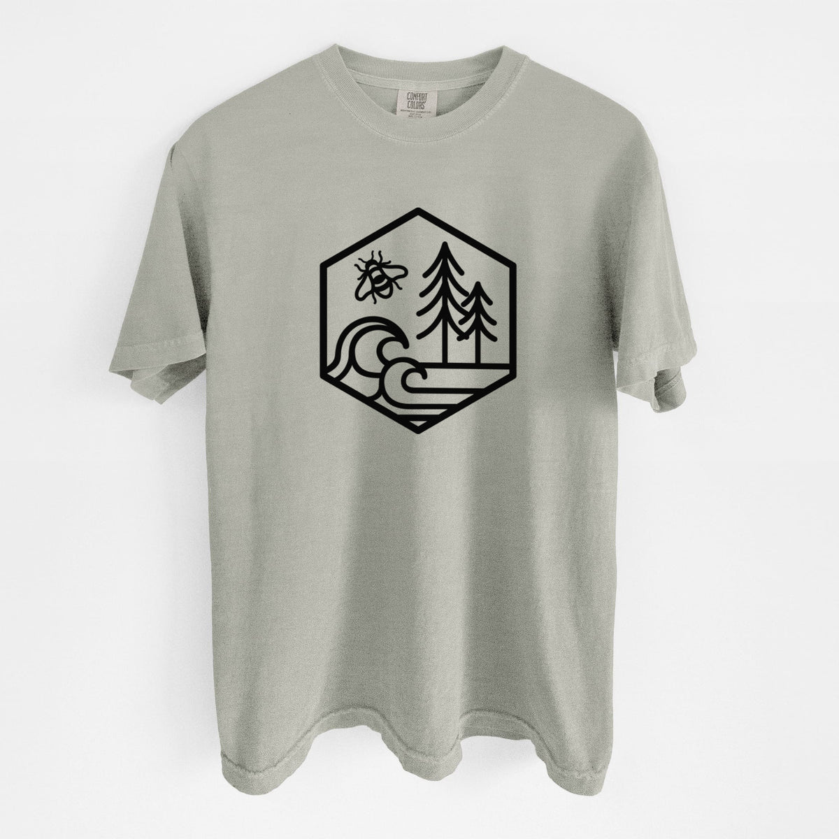 Sandstone beige Comfort Colors t-shirt laid flat, printed with a black line art hexagon holding a bee, ocean waves and pine trees.