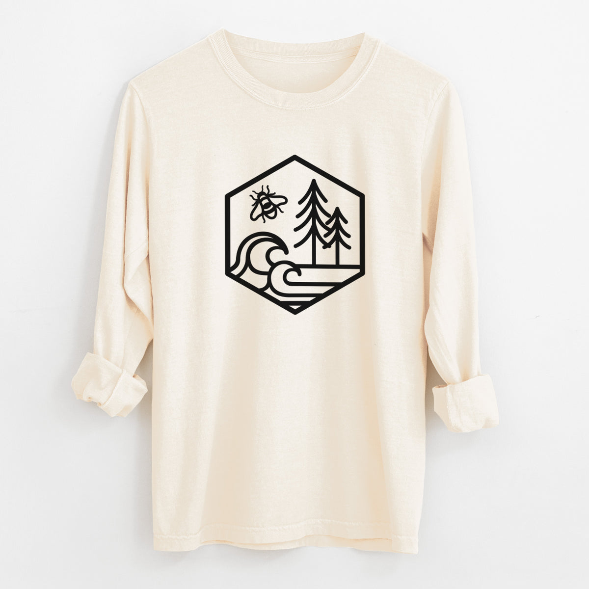 Ivory Comfort Colors long sleeve shirt laid flat with the cuffs rolled, printed with a black line art hexagon holding a bee, ocean waves and pine trees.