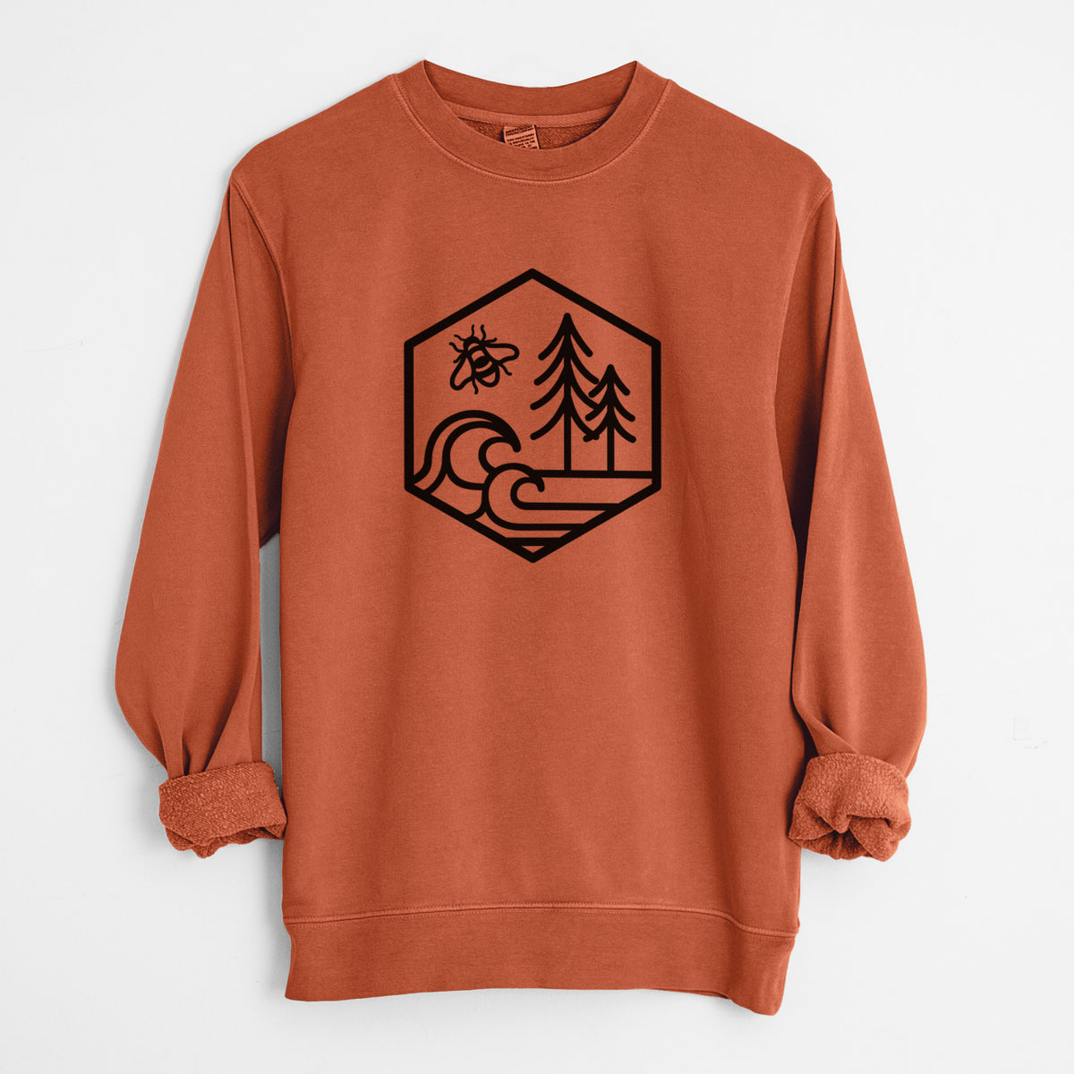 Amber orange pigment dyed crewneck sweatshirt laid flat with the sleeves rolled, printed with a black line art hexagon holding a bee, ocean waves and pine trees.