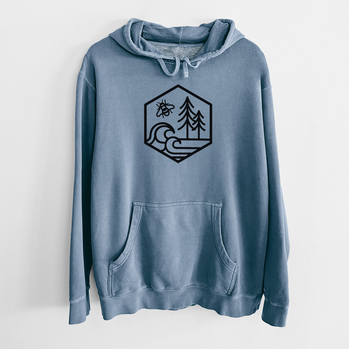 Slate blue pigment dyed hoodie laid flat, printed with a black line art hexagon holding a bee, ocean waves and pine trees.