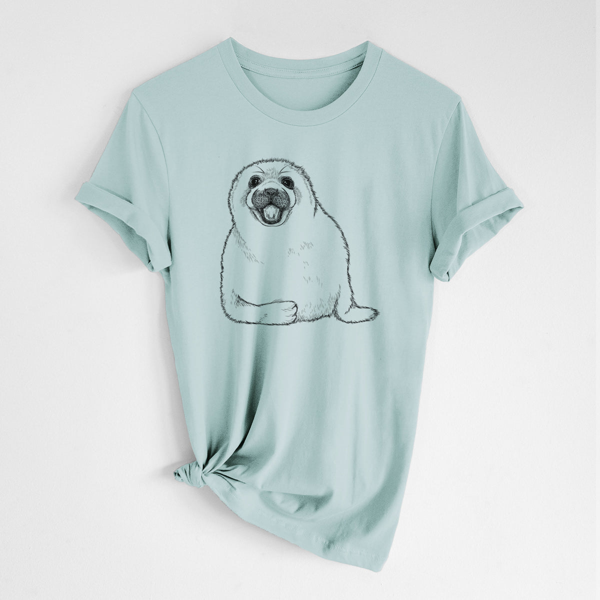 Dusty blue lightweight cotton t-shirt laid flat with the sleeves rolled, printed with a black ink illustration of a smiling harp seal pup lying down.