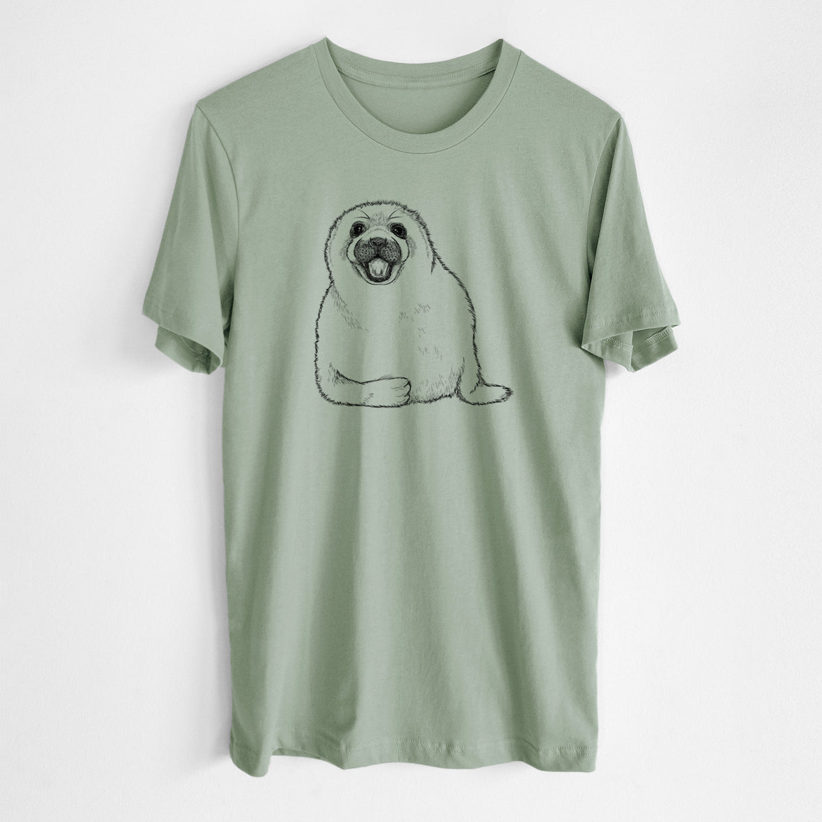 Sage green lightweight cotton t-shirt laid flat, printed with a black ink illustration of a smiling harp seal pup lying down.