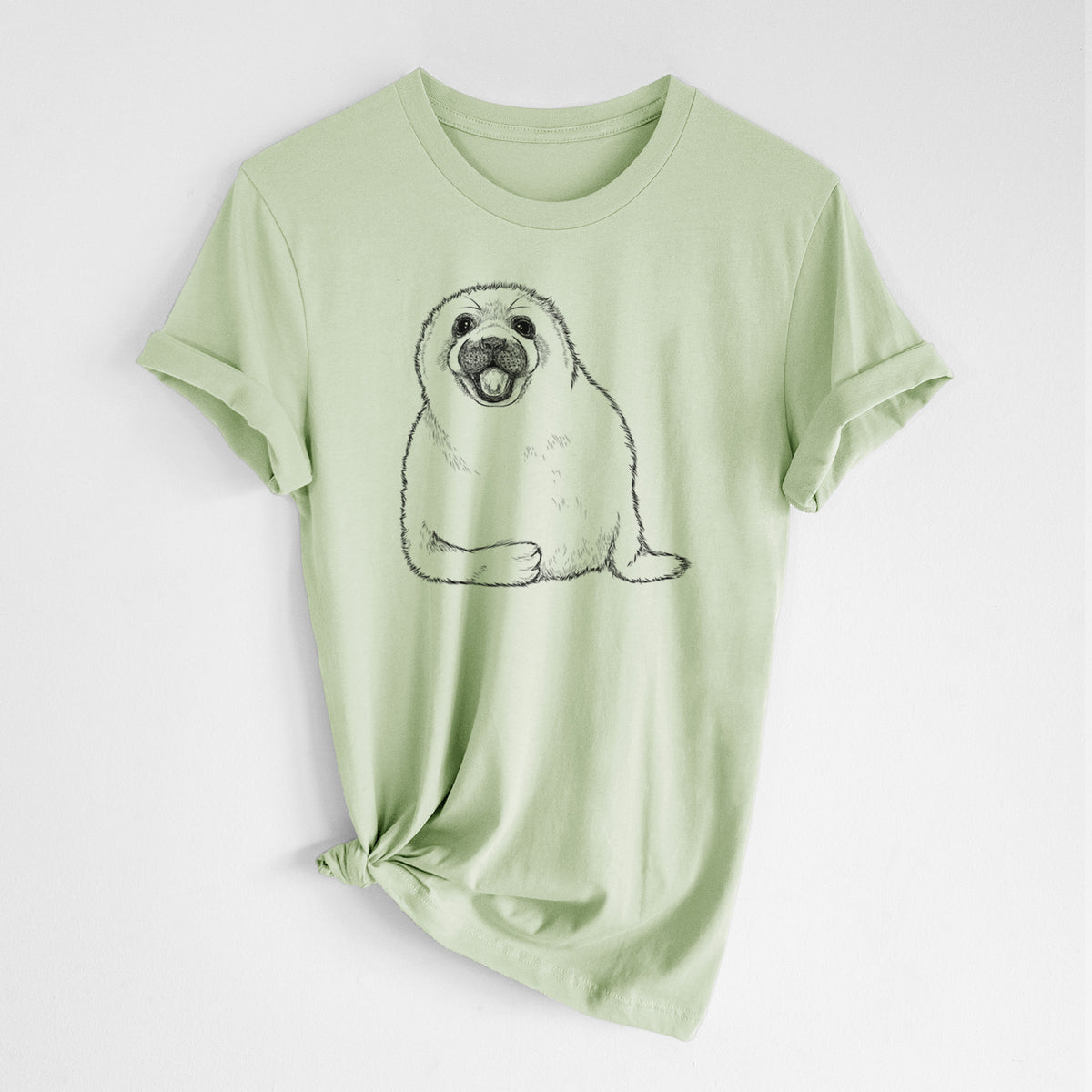 Spring green lightweight cotton t-shirt laid flat with the sleeves rolled, printed with a black ink illustration of a smiling harp seal pup lying down.