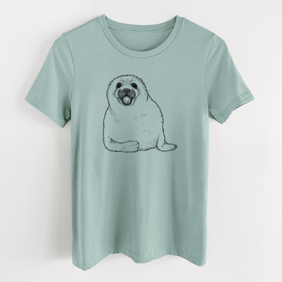 Dusty blue women's relaxed fit cotton t-shirt laid flat, printed with a black ink illustration of a smiling harp seal pup lying down.