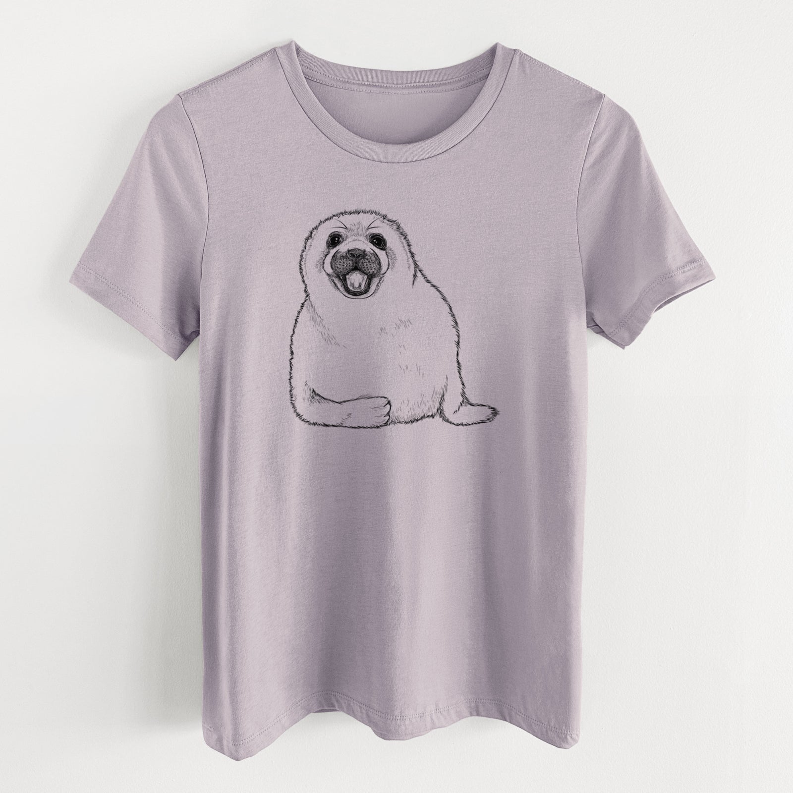 Light violet women's relaxed fit cotton t-shirt laid flat, printed with a black ink illustration of a smiling harp seal pup lying down.