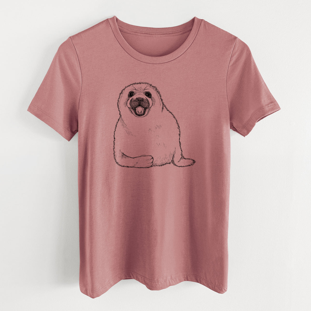 Mauve pink women's relaxed fit cotton t-shirt laid flat, printed with a black ink illustration of a smiling harp seal pup lying down.