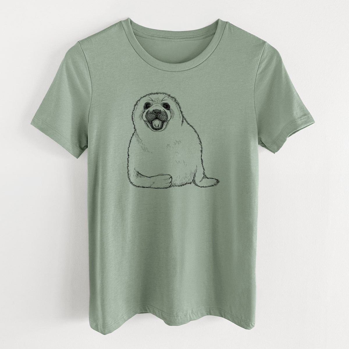 Sage green women's relaxed fit cotton t-shirt laid flat, printed with a black ink illustration of a smiling harp seal pup lying down.