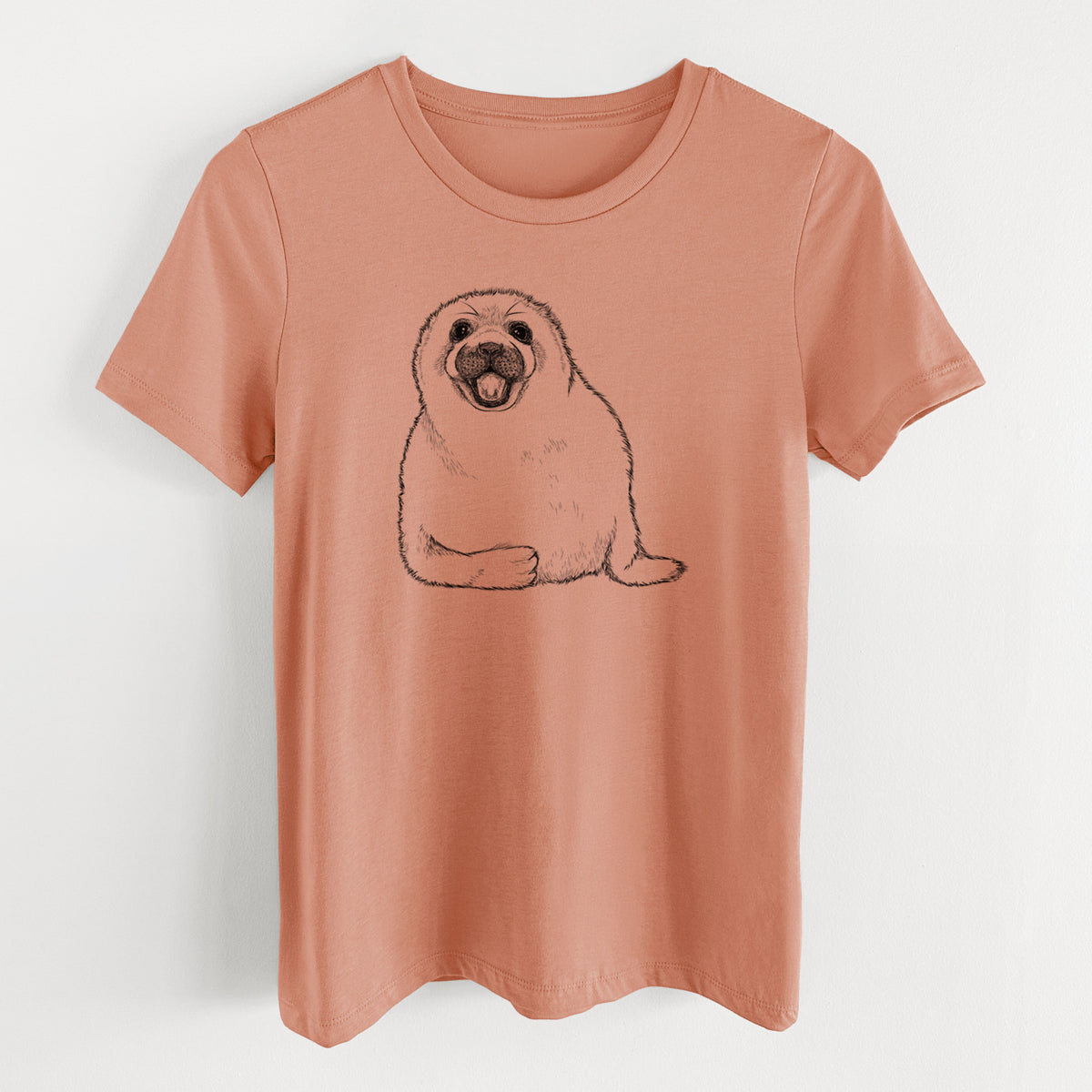 Terracotta orange women's relaxed fit cotton t-shirt laid flat, printed with a black ink illustration of a smiling harp seal pup lying down.