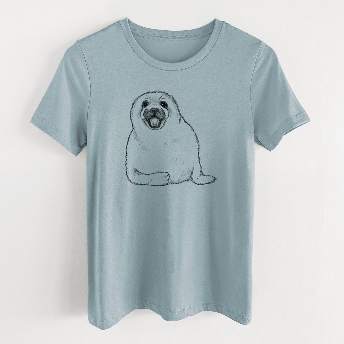 Vintage denim women's relaxed fit cotton t-shirt laid flat, printed with a black ink illustration of a smiling harp seal pup lying down.