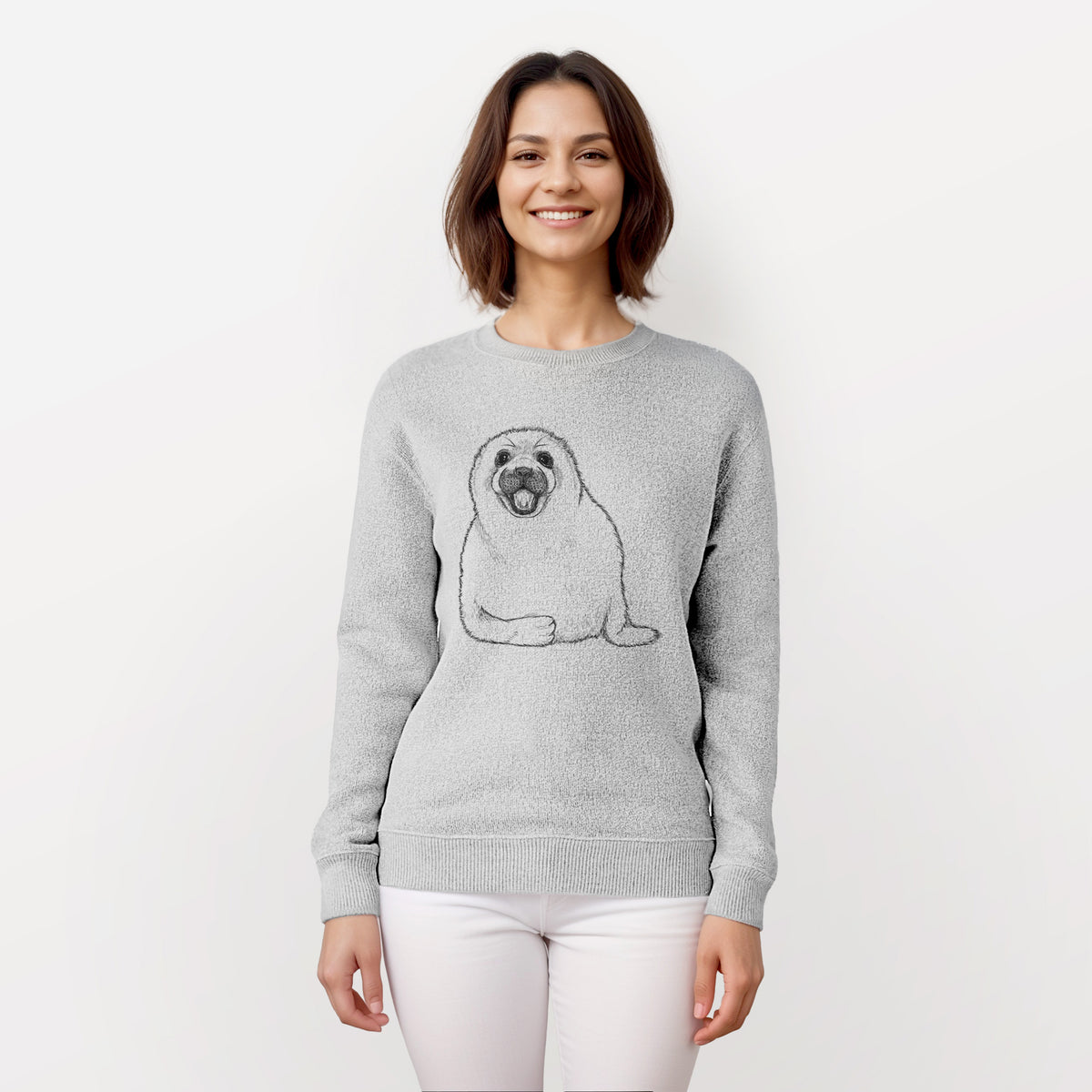 Woman wearing a knit sweatshirt printed with a black ink illustration of a smiling harp seal pup lying down.