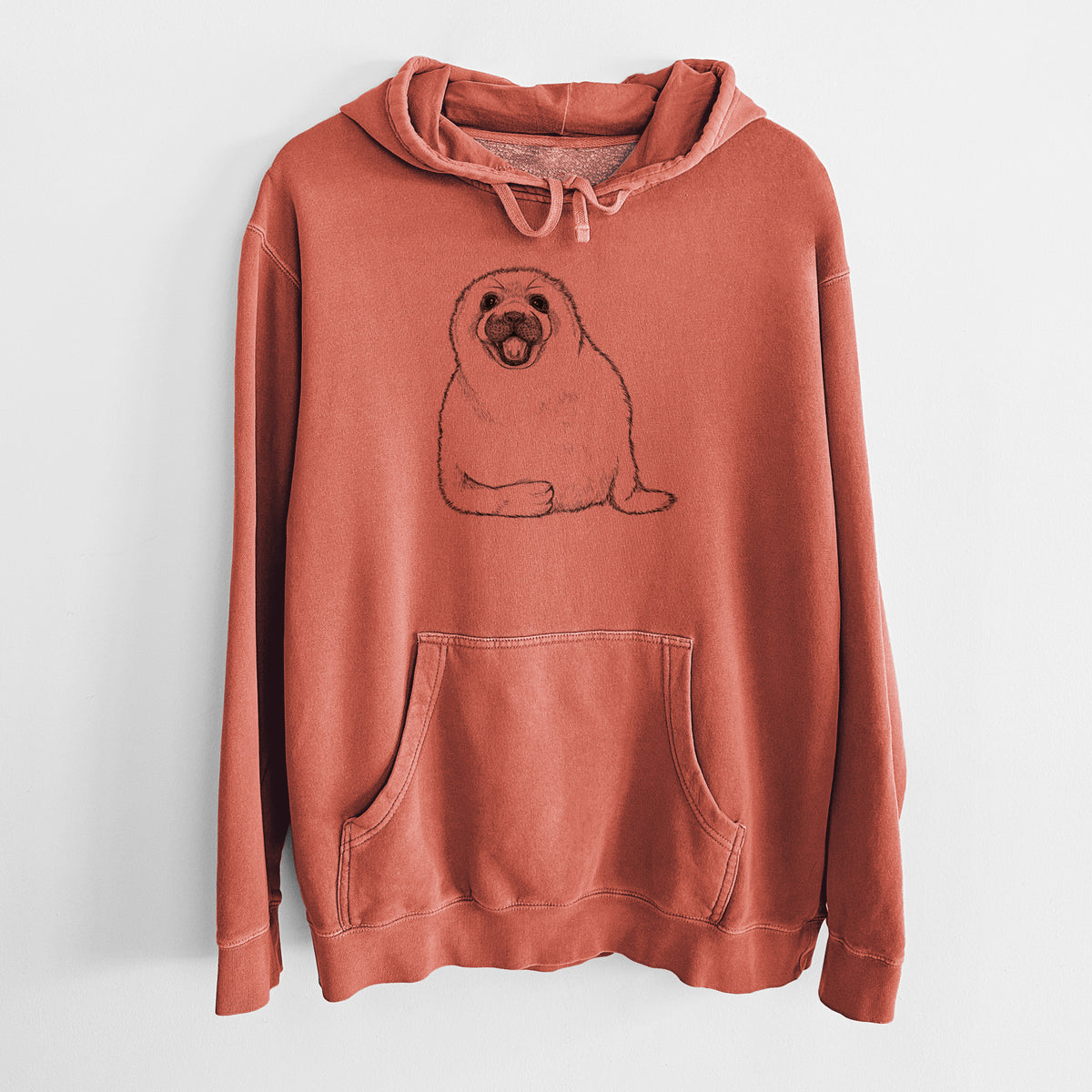 Amber orange pigment dyed hoodie laid flat, printed with a black ink illustration of a smiling harp seal pup lying down.