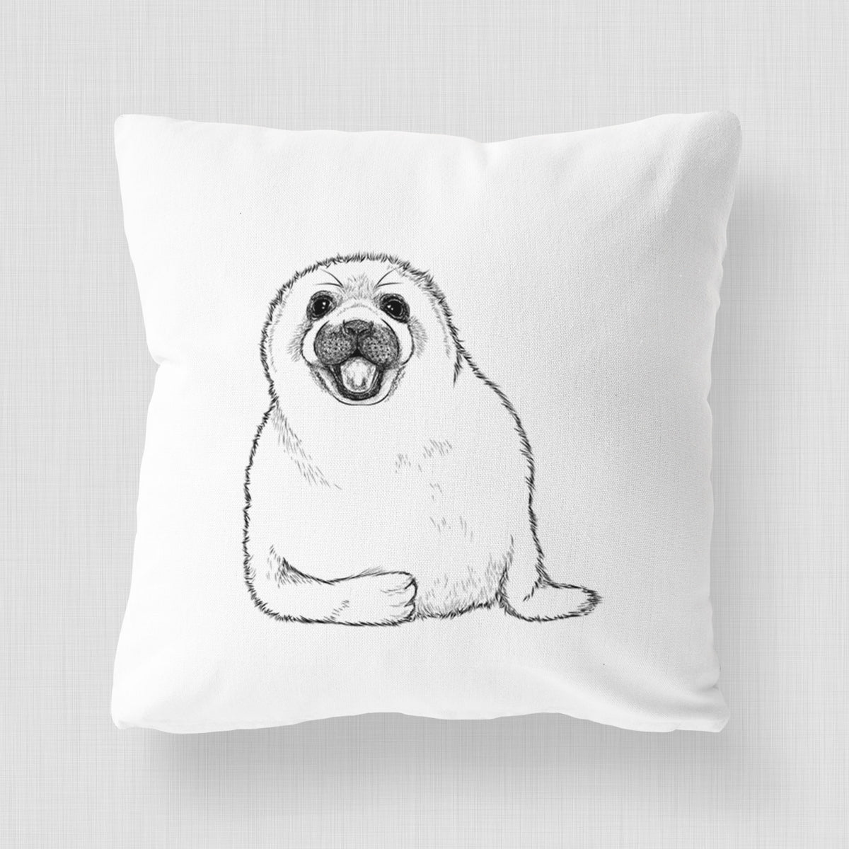 White pillow cover printed with a black ink illustration of a smiling harp seal pup lying down.