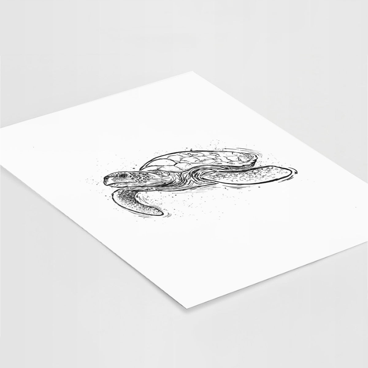Art print of a black ink illustration of a hawksbill sea turtle swimming, with a patterned shell, lying at an angle on a white surface.