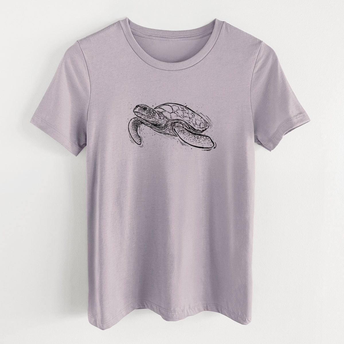 Light violet women's relaxed fit cotton t-shirt laid flat, printed with a black ink illustration of a hawksbill sea turtle swimming, with a patterned shell.